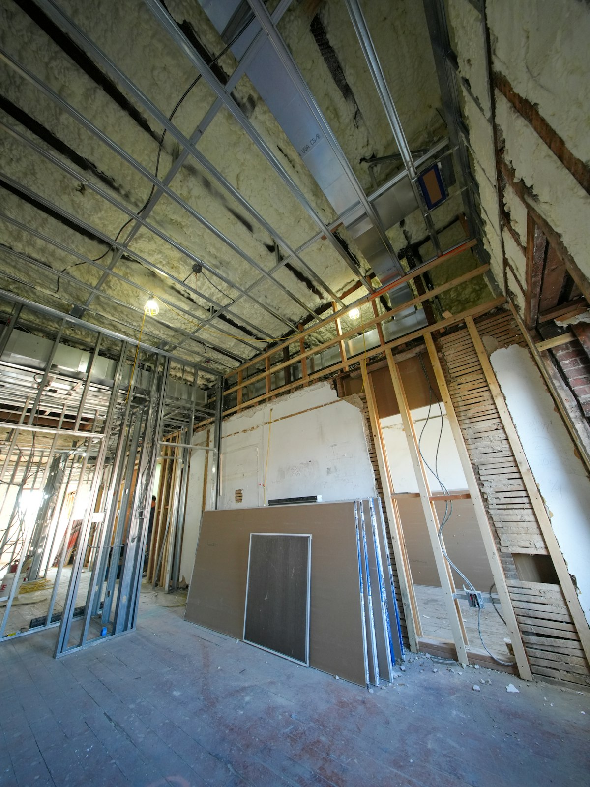 Interior build-out with metal stud framing and staged drywall sheets